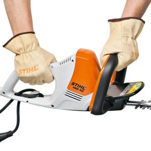 Stihl HSE 52 elektryczne nożyce do żywopłotów w rękach ogrodnika w rękawicach.