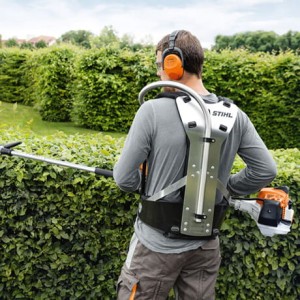 Mężczyzna używający Stihl HL 94 C-E Nożyce spalinowe na wysięgniku do przycinania żywopłotu.