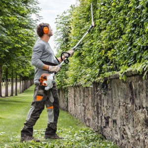 Mężczyzna przycinający żywopłot za pomocą Stihl HL 94 C-E Nożyce spalinowe na wysięgniku.
