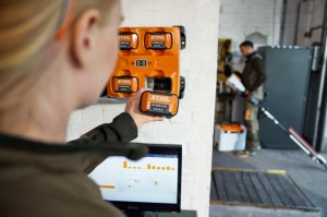 Osoba trzymająca Stihl AP 500 S Akumulator przy stacji ładującej w warsztacie.