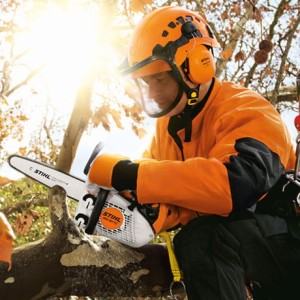 Operator w pomarańczowym kasku używający Stihl MS 151 TC-E Pilarki spalinowej do pielęgnacji drzew.