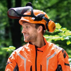 Mężczyzna w hełmie Stihl ADVANCE X-Vent i kurtce ochronnej w lesie.