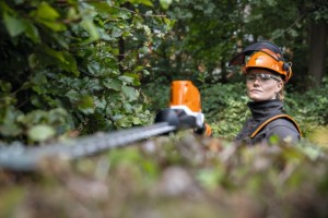 "Stihl HLA 86 Akumulatorowe nożyce do żywopłotów w użyciu przez osobę ubraną w sprzęt ochronny"