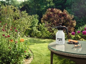 Stihl SG 11 Opryskiwacz ręczny w ogrodzie obok rękawic i sekatora.