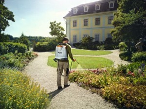 Mężczyzna używający Stihl SG 51 Opryskiwacz plecakowy 12l w ogrodzie przy rezydencji.