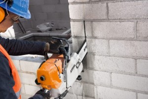 Stihl GS 461 Pilarka do betonu podczas cięcia ściany ceglanej w rękach pracownika.