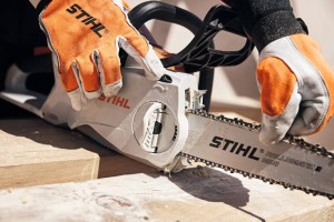 Ręce w rękawicach obsługujące Stihl MSA 200 C-B Pilarka akumulatorowa.
