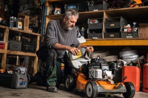 Mężczyzna konserwujący Stihl RM 756 YC kosiarkę spalinową w garażu.