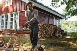Mężczyzna tnący drzewo pod domem przy pomocy pilarki spalinowej Stihl MS 212.