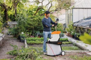 Mężczyzna używa Stihl GHE 135 L Rozdrabniacza, cichego rozdrabniacza elektrycznego ze zintegrowanym zbiornikiem 60 l w ogrodzie.