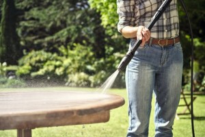 Osoba używająca Stihl RE 80 Myjka wysokociśnieniowa do czyszczenia stołu ogrodowego w ogrodzie.