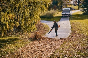 Mężczyzna używający dmuchawy Stihl BGA 300 do usuwania liści z chodnika.