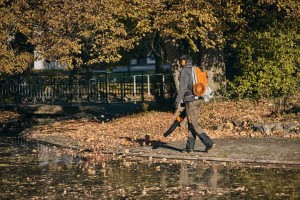 Pracownik używający Stihl BGA 300 bez akumulatora i ładowarki do usuwania liści.