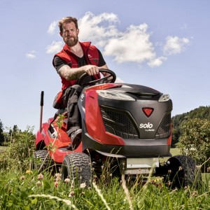 Mężczyzna siedzący na czerwonym traktorku ogrodowym Traktor Alko T18-103.4 HD-A V2 COMFORT.