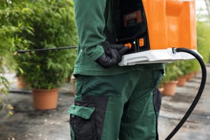 Pracownik ogrodniczy używa Stihl SGA 85 Akumulatorowy opryskiwacz w ogrodzie.