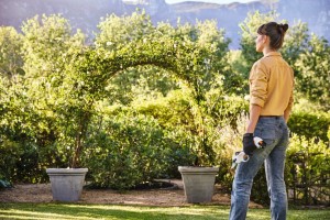 Kobieta trzymająca Stihl ASA 20 Sekator akumulatorowy na tle ogrodu.