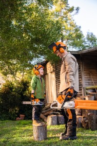 Dziecko i dorosły z piłami Stihl, obaj w kaskach ochronnych Stihl.
