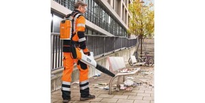 Pracownik używający Stihl BGA 100 Dmuchawa akumulatorowa do sprzątania liści na chodniku.