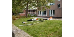 Narzędzia ogrodowe Stihl KMA 135 R KombiMotor bez akumulatora i ładowarki na trawie przed budynkiem.