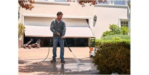 Stihl RE 90 Myjka, mężczyzna myje podjazd przed domem wysokociśnieniową myjką.