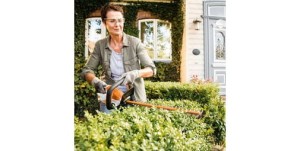 Kobieta używająca Stihl HSA 45, Nożyce akumulatorowe ze zintegrowanym akumulatorem, przycinająca żywopłot.