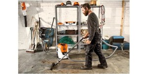 Mężczyzna używa Stihl SE 62 E Odkurzacza do czyszczenia na sucho i mokro w warsztacie.