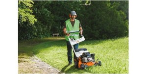 Mężczyzna koszący trawę kosiarką spalinową Stihl RM 756 YC na zielonym trawniku.