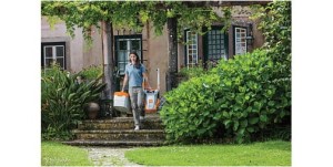 Kobieta wychodząca z domu, trzymająca Stihl RME 235 Kosiarkę do małych trawników.
