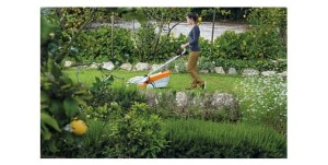 Kobieta kosząca trawę małą kosiarką Stihl RME 235 w ogrodzie.