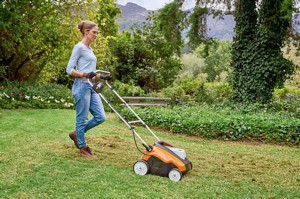 Kobieta używa Stihl RLA 240 Kompaktowy wertykulator z wałkiem aeracyjnym, bez akumulatora i ładowarki w ogrodzie.