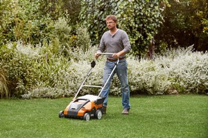 Mężczyzna używający Stihl RLA 240 Kompaktowy wertykulator z wałkiem aeracyjnym, bez akumulatora i ładowarki na trawniku.