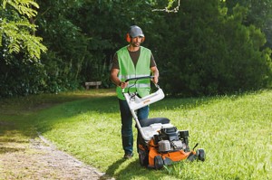 Mężczyzna korzystający z kosiarki spalinowej Stihl RM 756 YC na trawniku.