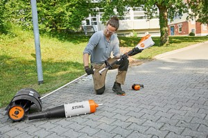 Mężczyzna używający Stihl KMA 135 R KombiMotor na ścieżce w parku.