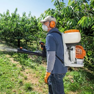 Mężczyzna używający Stihl SR 200 Opryskiwacz 10l w sadzie.