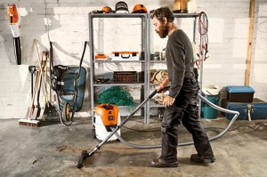 Mężczyzna sprzątający garaż odkurzaczem Stihl SE 62 E Odkurzacz do czyszczenia na sucho i na mokro z automatycznym włącznikiem.