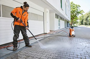 Mężczyzna używający Stihl RE 170 PLUS Myjka do czyszczenia kostki brukowej przed domem.
