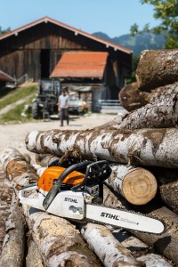 Stihl MS 271 Pilarka spalinowa na stosie drewna przed drewnianą stodołą.