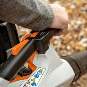 Ręka obsługująca Stihl BGA 200 Dmuchawa akumulatorowa w jesiennej scenerii.