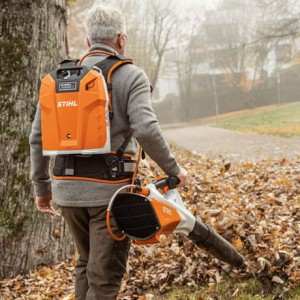Mężczyzna używający Stihl BGA 200 Dmuchawy akumulatorowej, usuwający liście w ogrodzie.