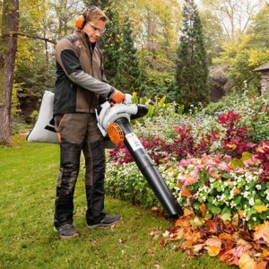 Mężczyzna używa Stihl SH 86 Odkurzacz spalinowy o dużej mocy do zbierania liści w ogrodzie.