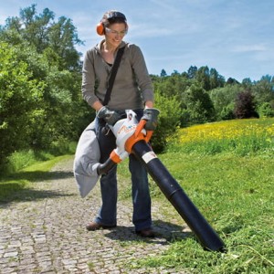 Kobieta używająca Stihl SHE 81 Odkurzacz elektryczny w ogrodzie.